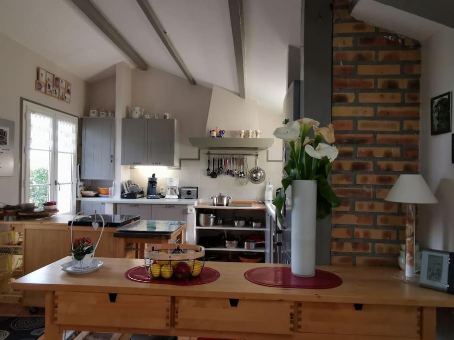 una cocina con una mesa con un jarrón de flores. en Gîte familial de charme entier en Gascogne, en Marseillan