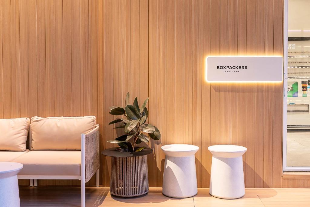 a waiting room with a couch and two stools at Boxpackers Pratunam in Bangkok