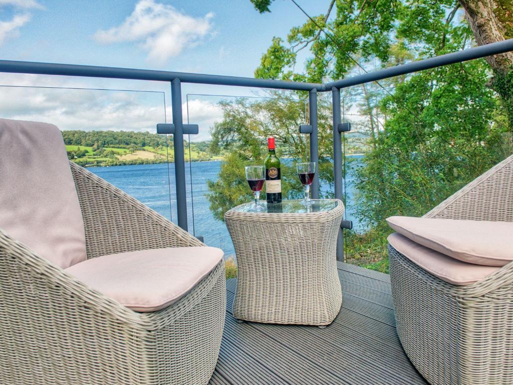 two glasses of wine sitting on a table on a deck at Vyrnwy Lakeside - Bala Lake in Bala