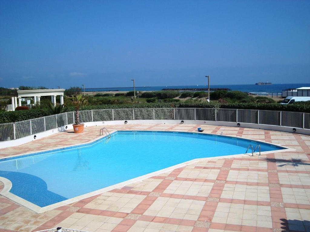duży niebieski basen na ceglanym patio w obiekcie SUNSET Charmant T2 avec coin cabine vue mer piscine Rochelongue Cap d'Agde w Cap d'Agde