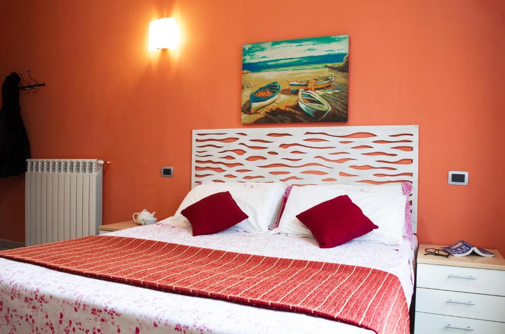 una camera con un letto con due cuscini rossi di Monolocale in Centro Tuttialmare Castellammare del Golfo Sicilia a Castellammare del Golfo