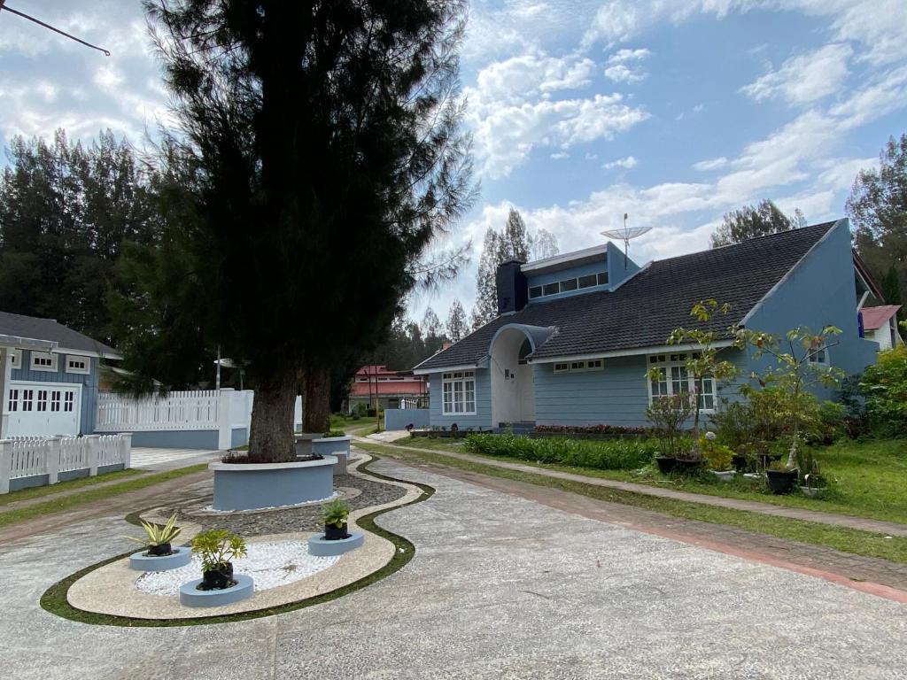 una casa con un árbol en medio de una entrada en Villa Berastagi Indah A17 - TEBU MANIS en Berastagi