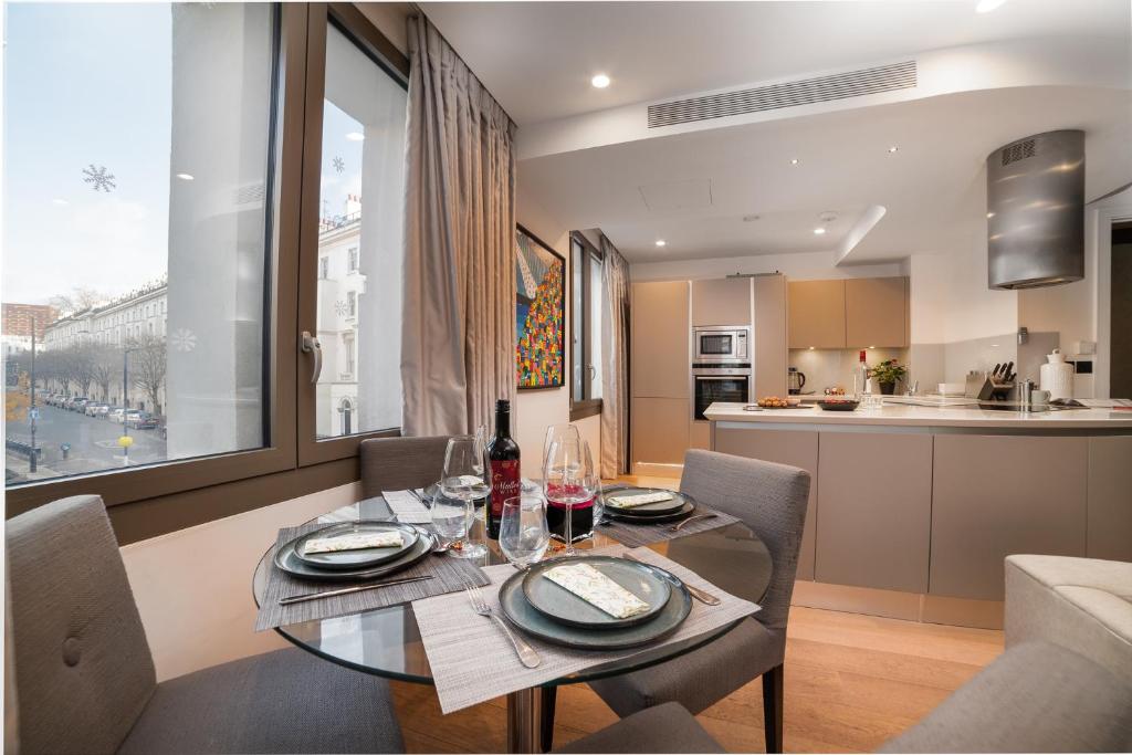 una sala da pranzo con tavolo e sedie e una cucina di Stunning Modern Apartment close to Hyde Park by UnderTheDoormat a Londra