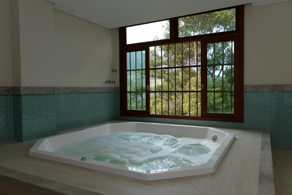 eine große Badewanne in einem Zimmer mit Fenster in der Unterkunft Vista Azul Apart Hotel - Vista Pedra Azul in Domingos Martins