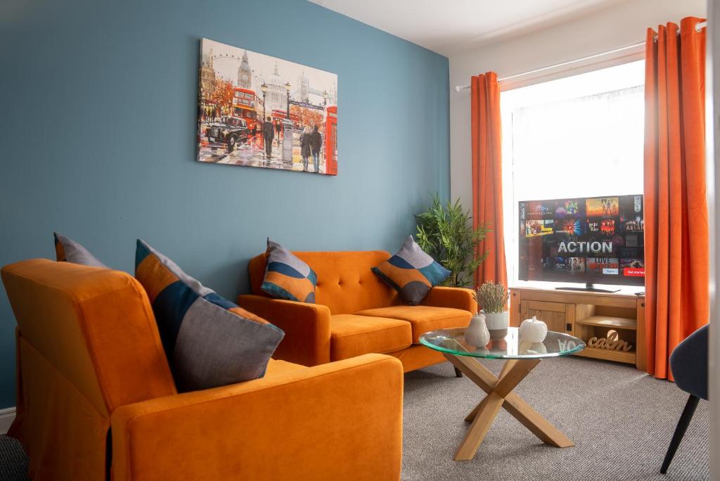 Sala de estar con 2 sillas de color naranja y mesa en Comfortable 4 Bedroom Home in Milton Keynes by HP Accommodation with Free Parking, WiFi & Sky TV en Milton Keynes