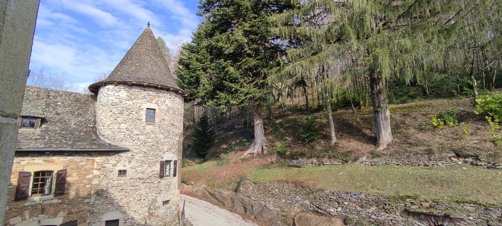 a stone building with a tower on a hill at Château de Chauvac - Chambres et table d'hôtes avec vue sur la rivière in Bassignac-le-Bas