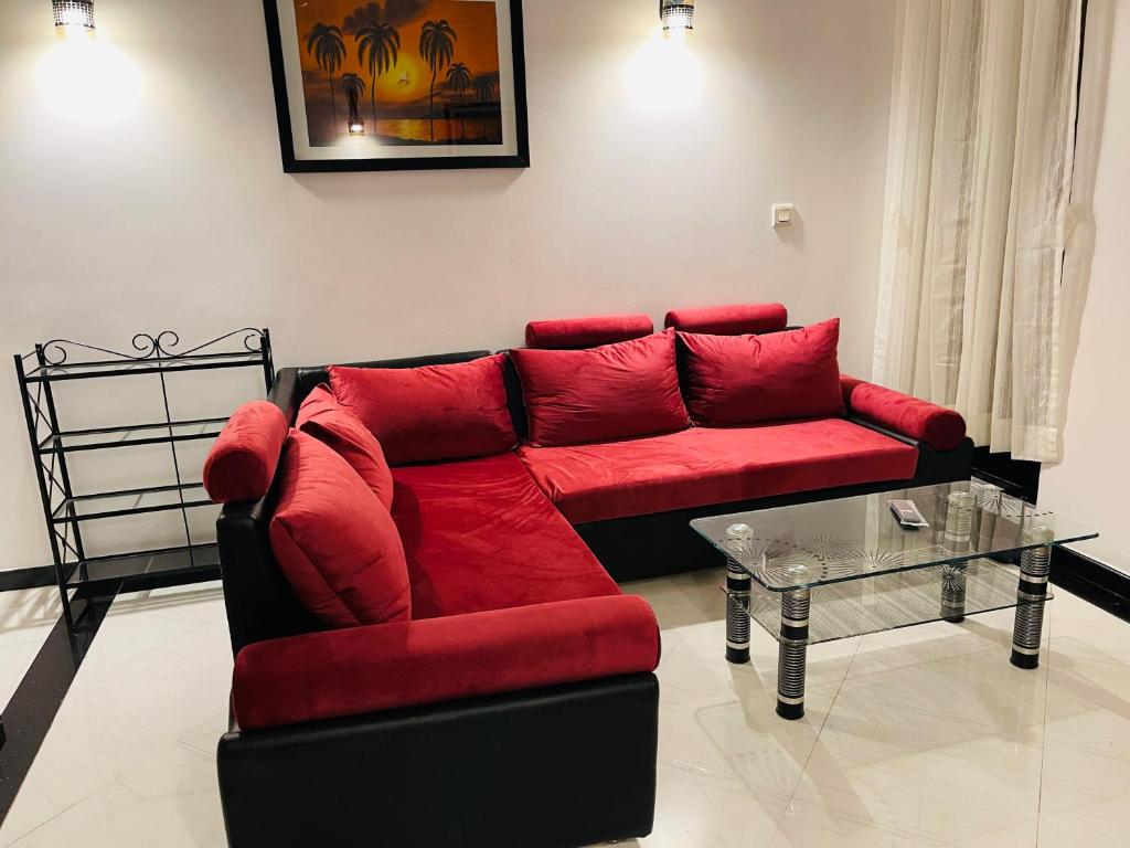 a living room with a red couch and a glass table at Riviera palms 1 Luxury 1 BHK apartment with Swimmimg Pool view- Arpora - near baga beach in Old Goa