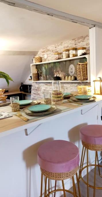 - une cuisine avec deux tabourets et un comptoir avec des assiettes dans l'établissement Gite Les Lanternes, à Rouen