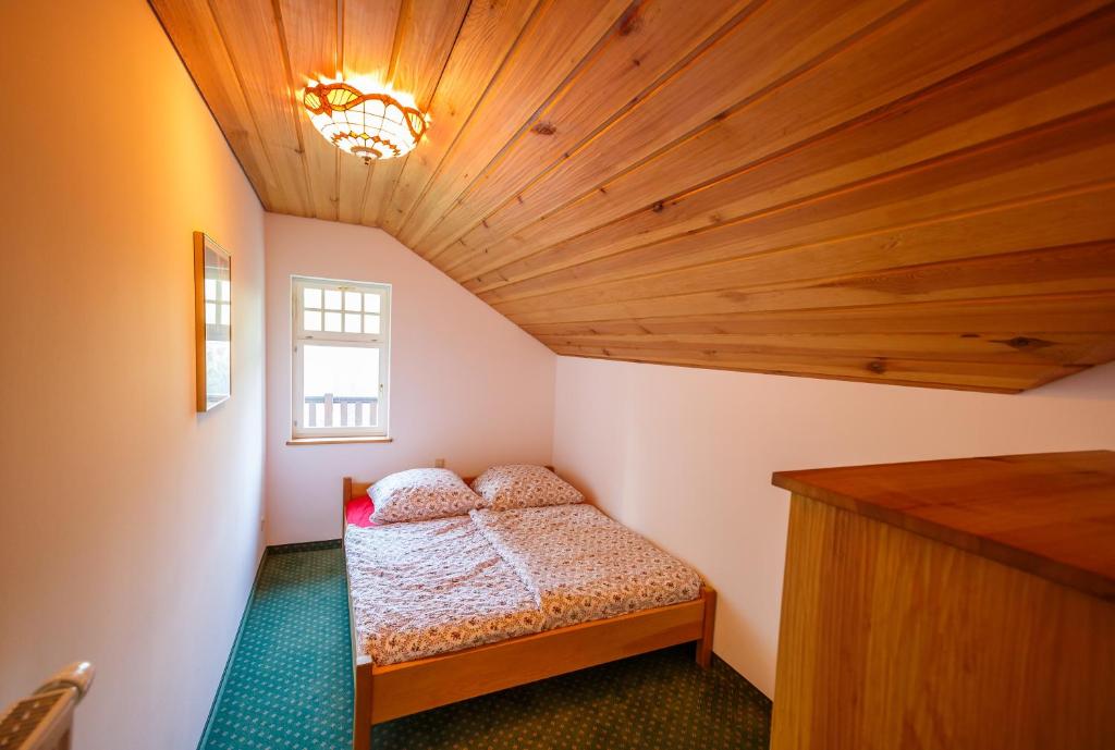 una piccola camera con letto e soffitto in legno di Haus Schrammsteinblick a Ostrau