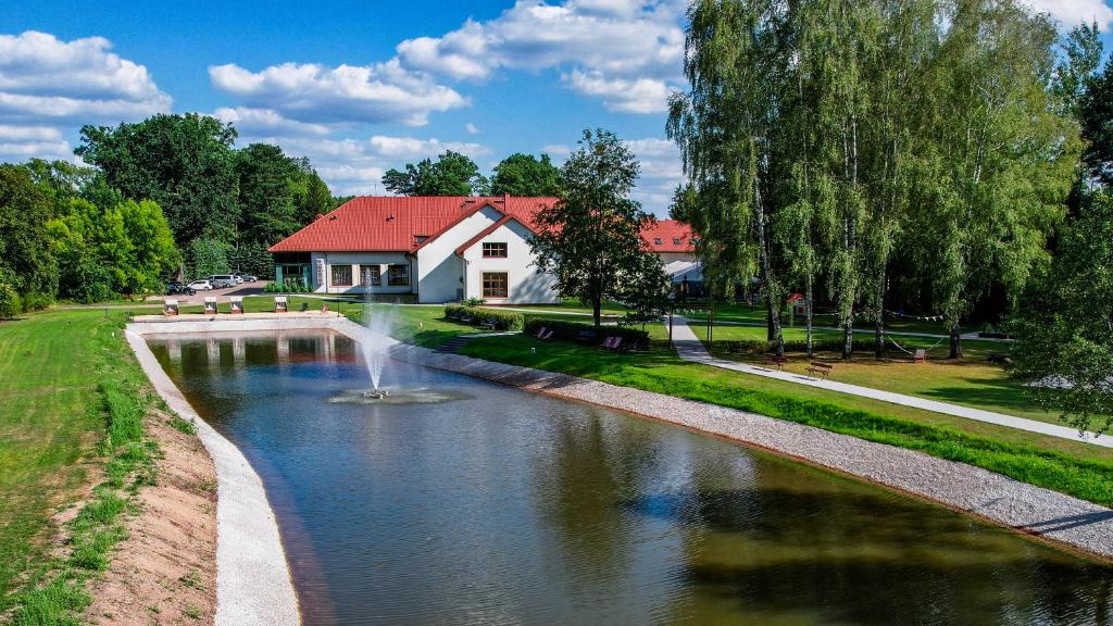 ein Haus mit einem Brunnen inmitten eines Flusses in der Unterkunft Hotel Prezydent in Spała