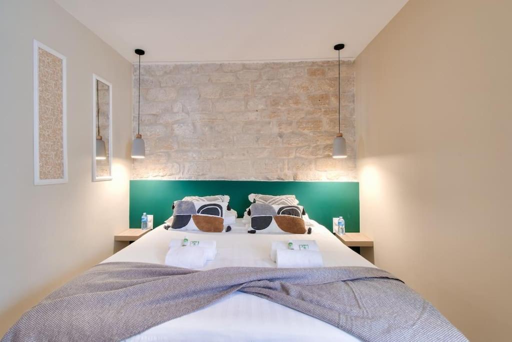 une chambre avec un grand lit avec un mur de briques dans l'établissement Cozy apartement historic Center Paris & Montmartre, à Paris
