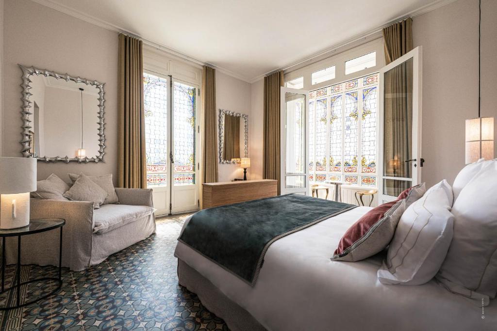 Hôtel Le Mosaïque في ناربون: غرفة نوم بسرير كبير وأريكة