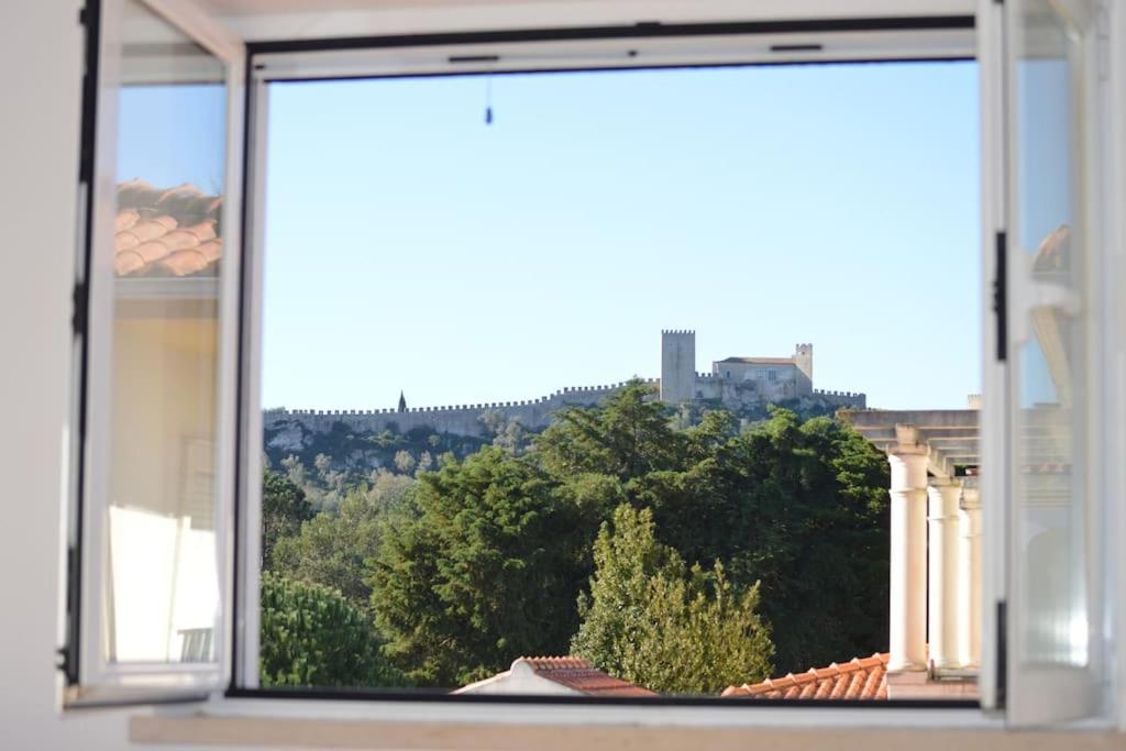 ein Fenster mit Blick auf Bäume und ein Gebäude in der Unterkunft Casa da Várzea - O Castelo à Janela!!! in Óbidos