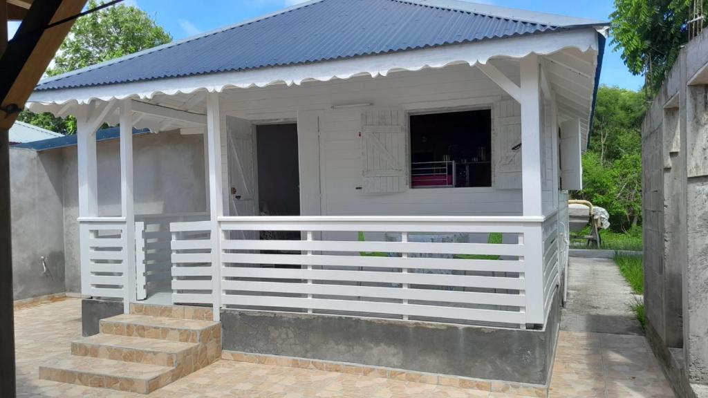 a white shed with a blue roof and stairs at Petit chalet vacance in Vidon