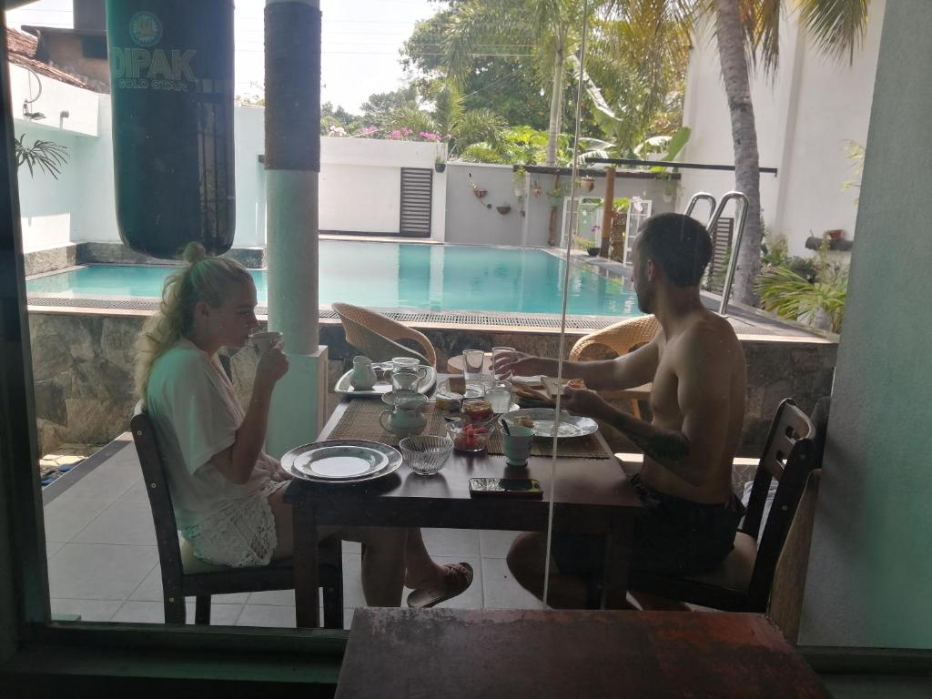 a man and a woman sitting at a table in front of a pool at Ibis in Udawalawe