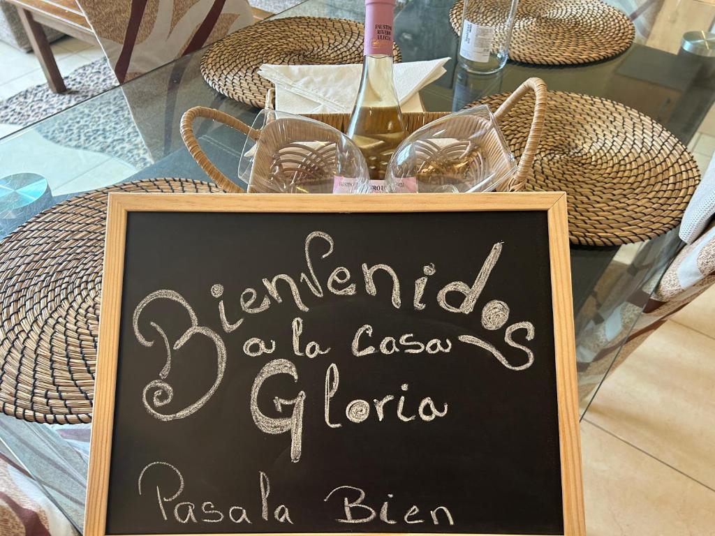 un cartel de pizarra frente a una mesa con copas de vino en Casa Gloria, en Los Abrigos