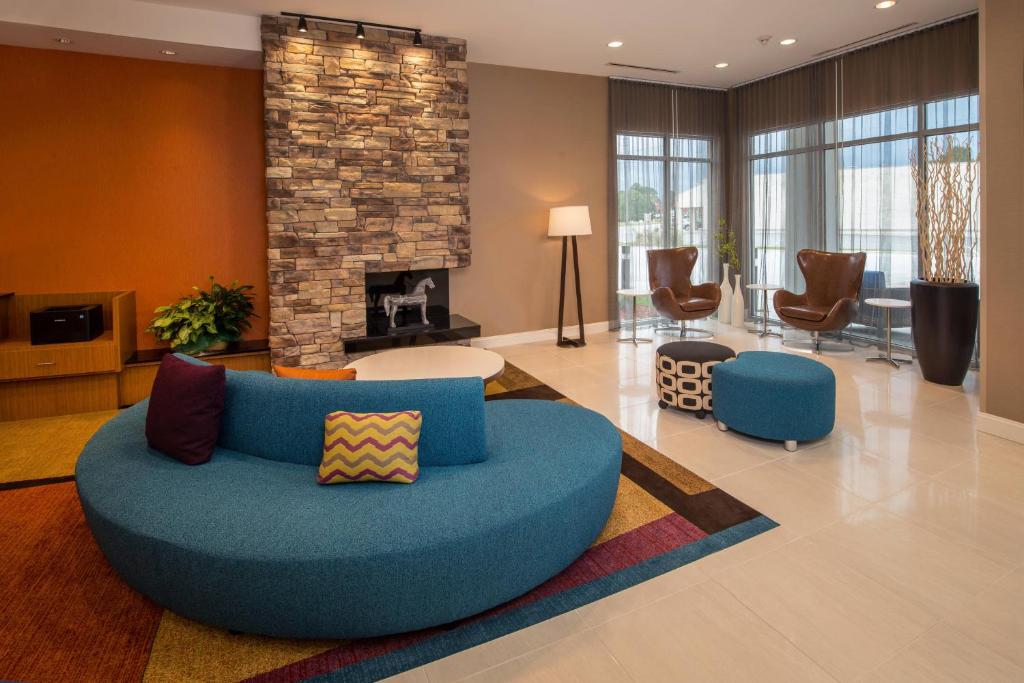 Fairfield Inn & Suites by Marriott Washington في واشنطن: غرفة معيشة مع أريكة زرقاء ومدفأة