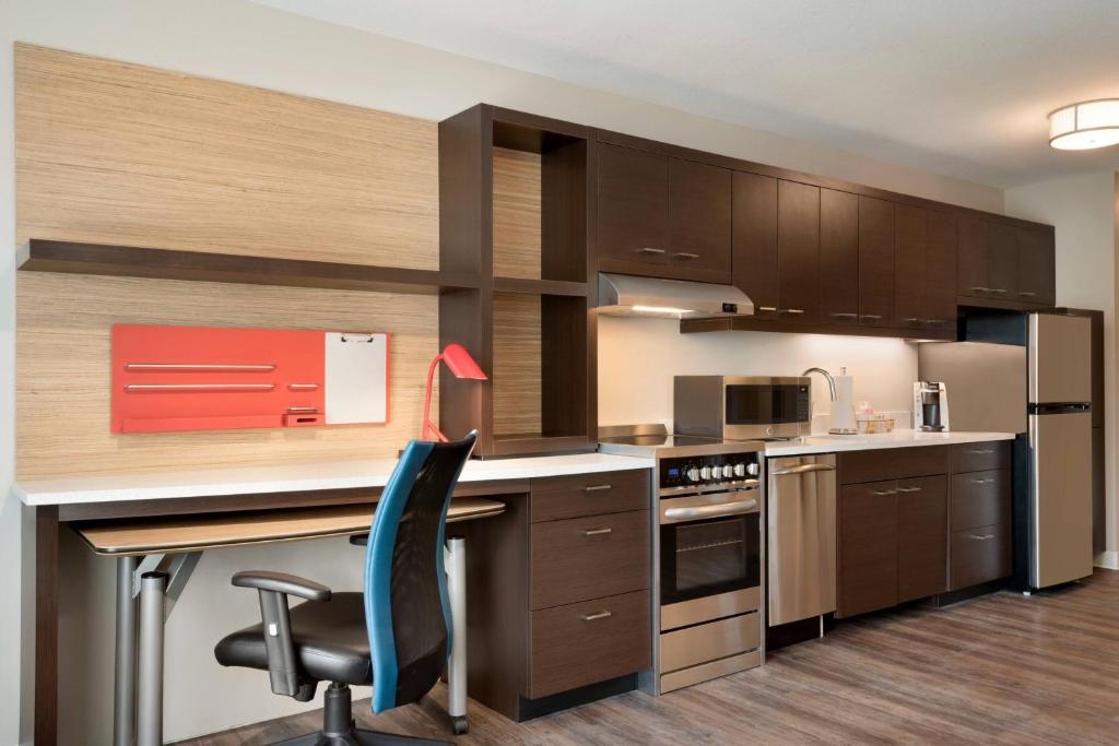 cocina con armarios marrones y escritorio con silla azul en TownePlace Suites by Marriott Joliet Minooka, en Minooka