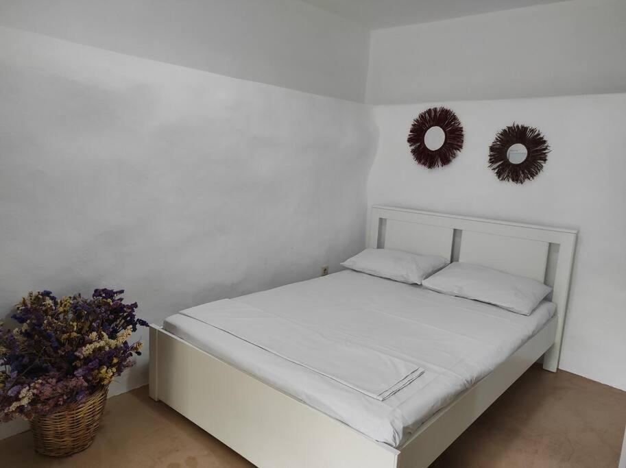1 cama blanca con 2 espejos en la pared en ELECTRAS LITTLE COTTAGE, en Ándros