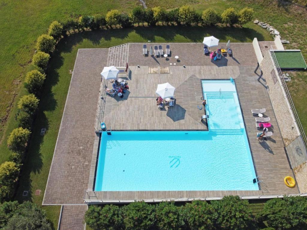 - une vue sur la piscine dotée de tables et de parasols dans l'établissement Domino Apt, à Sarnico