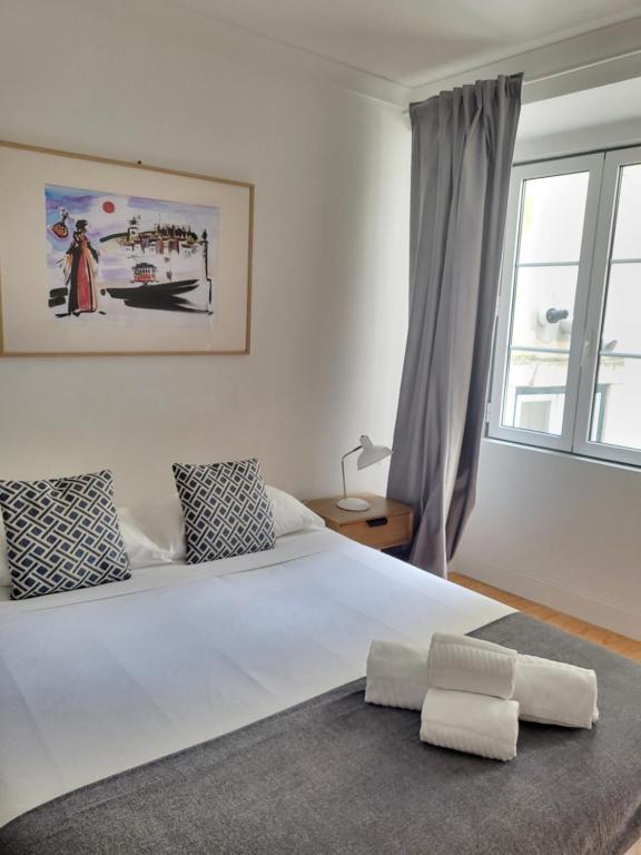 a bedroom with a large white bed with a window at Alfama Apartments Services in Lisbon