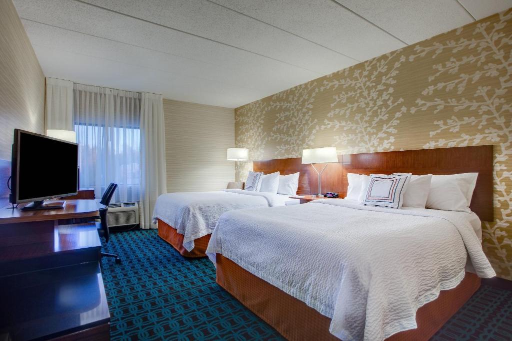 a hotel room with two beds and a flat screen tv at Fairfield Inn by Marriott Burlington Williston in Burlington