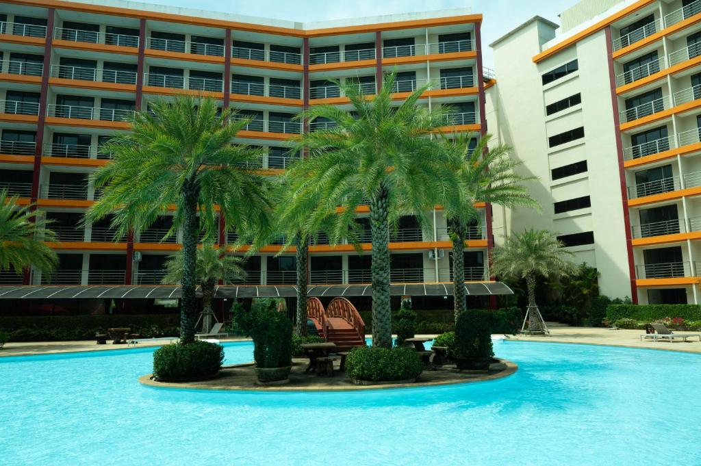 a pool with palm trees in front of a building at 777 Beach Condo Phuket in Mai Khao Beach