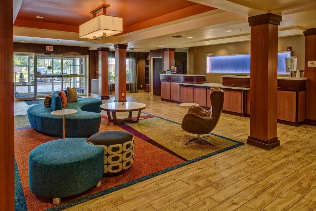 a hotel lobby with blue chairs and a television at Fairfield by Marriott Russellville in Russellville