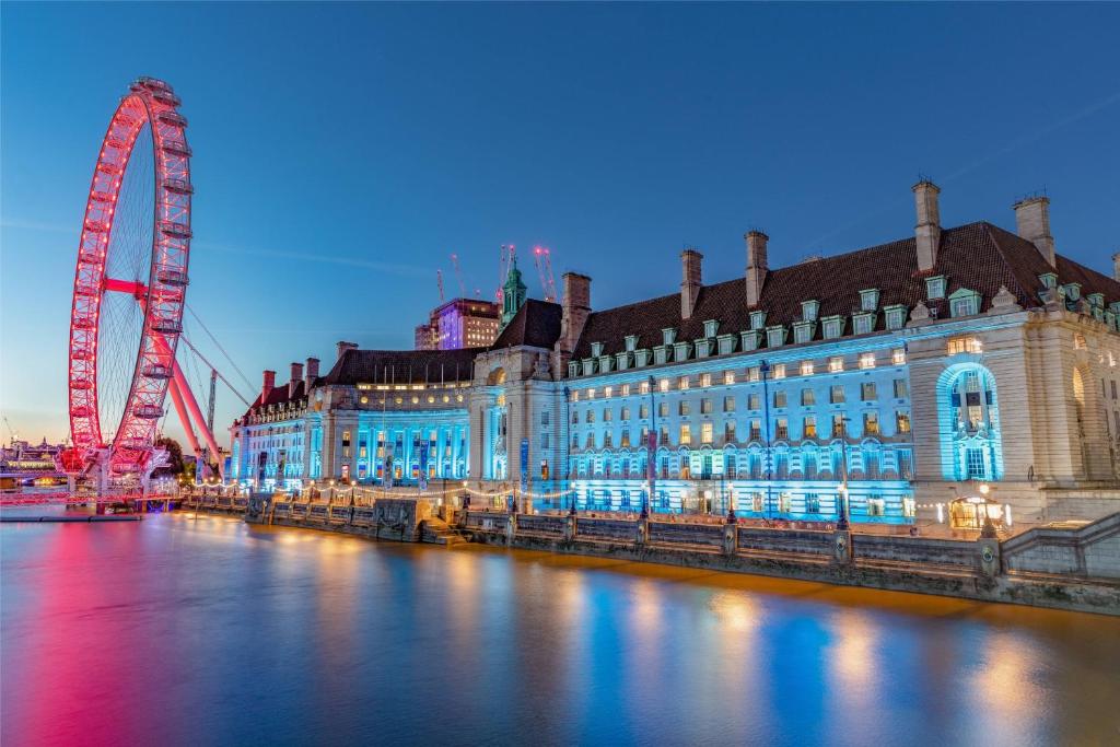 um grande edifício ao lado de um rio com uma roda gigante em London Marriott Hotel County Hall em Londres