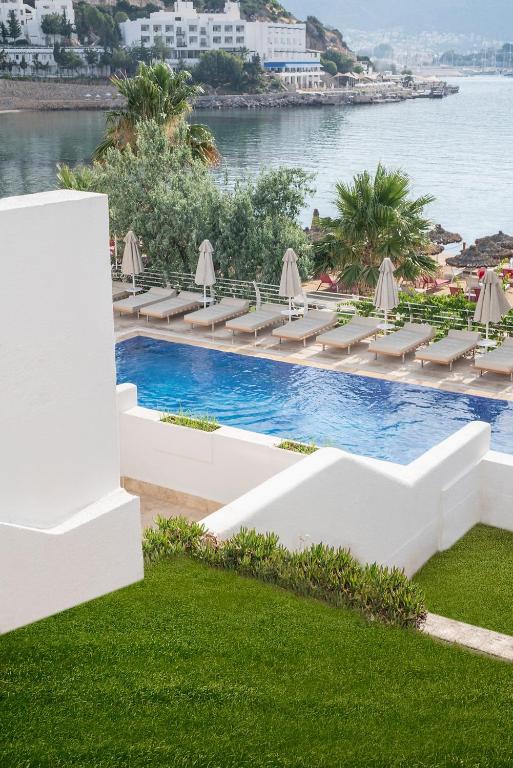 a pool with chairs and umbrellas next to the water at Prive Hotel Bodrum - Adult Only in Bodrum City