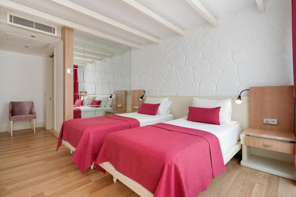 a bedroom with two beds with red sheets at Prive Hotel Bodrum - Adult Only in Bodrum City