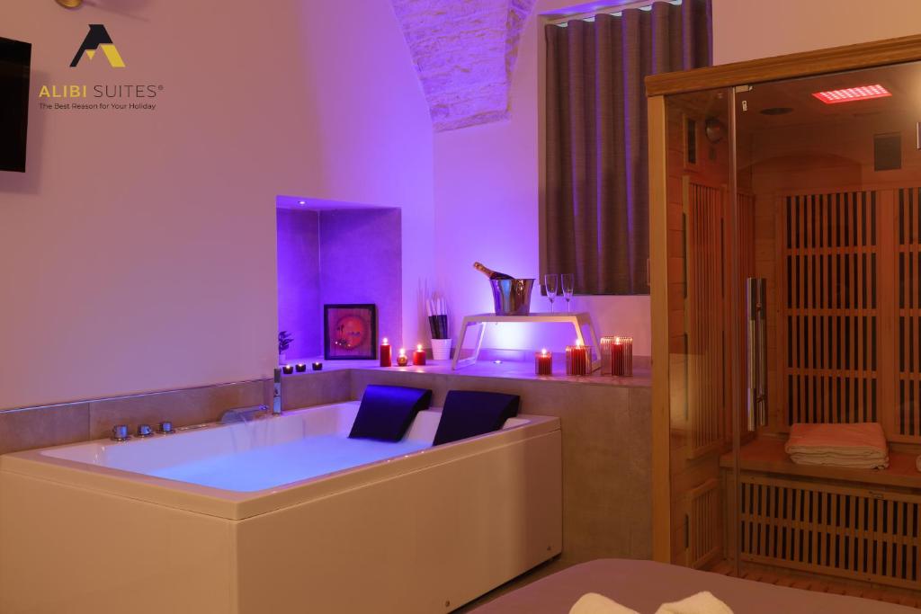 uma grande banheira na casa de banho com iluminação roxa em [Alibi Suites] Suite Fieramosca Spa & Relax em Ruvo di Puglia