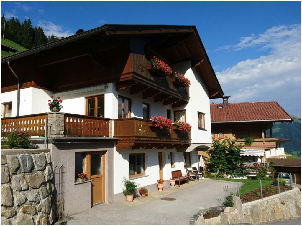 a large white house with a balcony with flowers at Haus Spitaler in Hippach