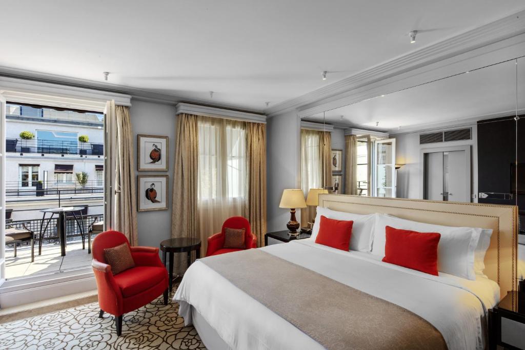 Cette chambre d'hôtel comprend un grand lit et des chaises rouges. dans l'établissement Prince de Galles, un hôtel Luxury Collection, Paris, à Paris