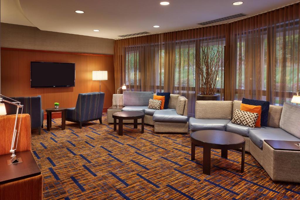 a living room with couches and a flat screen tv at Courtyard by Marriott Kansas City Shawnee in Shawnee