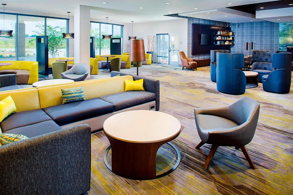 a lobby with couches and tables and chairs at Courtyard by Marriott Dallas Carrollton and Carrollton Conference Center in Carrollton