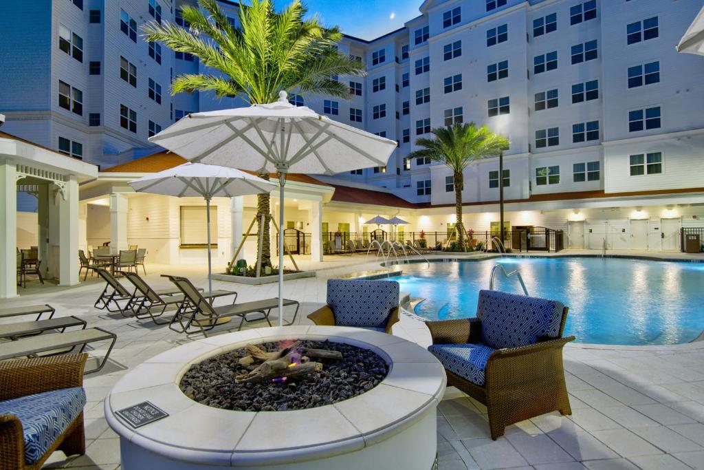 a hotel with a pool and a patio with a fire pit at Residence Inn by Marriott Orlando at FLAMINGO CROSSINGS Town Center in Orlando