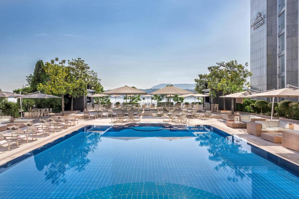 una piscina con sedie e ombrelloni in un hotel di Hotel President Wilson, a Luxury Collection Hotel, Geneva a Ginevra