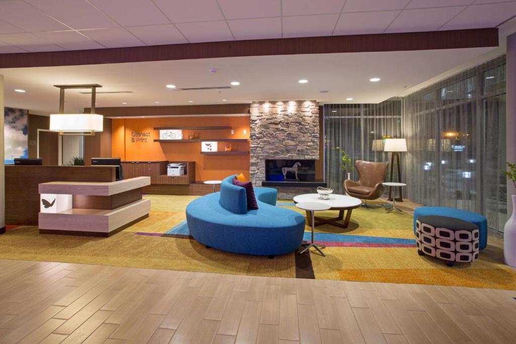 a lobby with blue chairs and a fireplace at Fairfield Inn & Suites by Marriott Burlington in Burlington