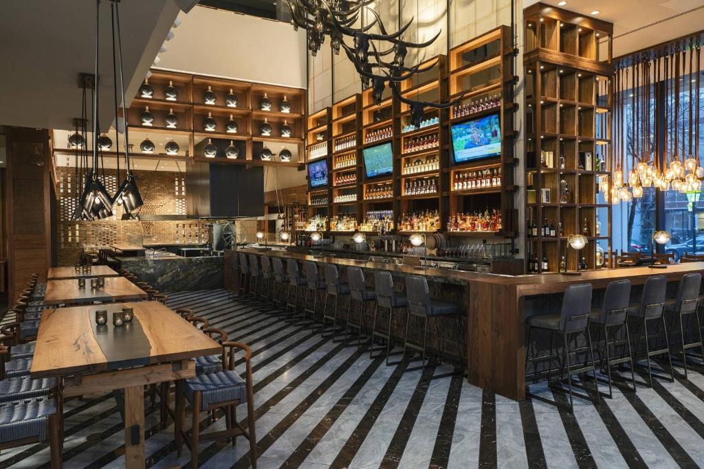 un bar en un restaurante con mesas y sillas de madera en The Worthington Renaissance Fort Worth Hotel, en Fort Worth