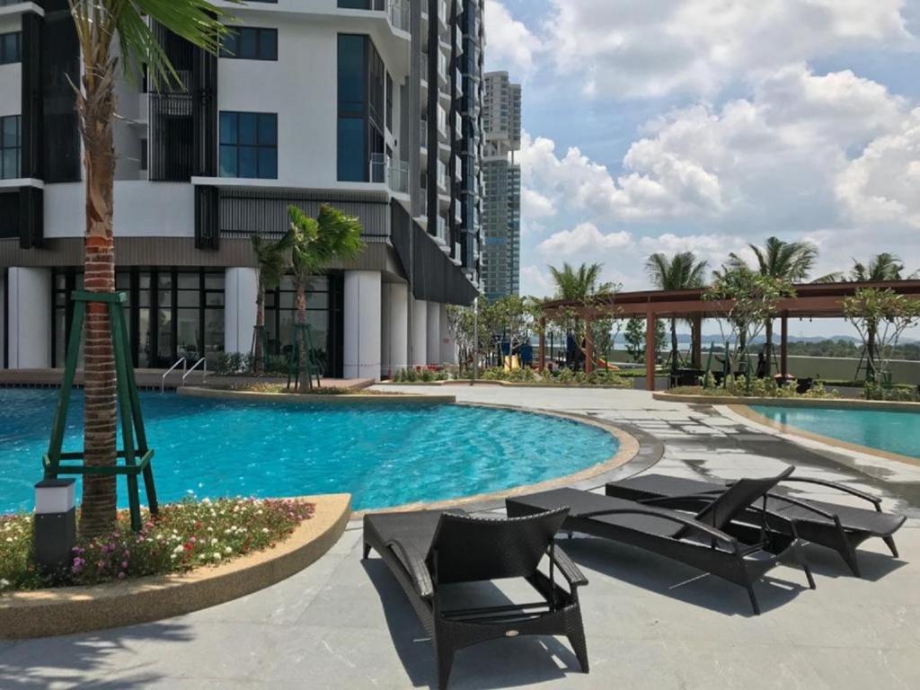 Una piscina con tumbonas al lado de un edificio. en Almas Suite-SS-Puteri Harbour Legoland-JB新山- SG新加坡, en Nusajaya