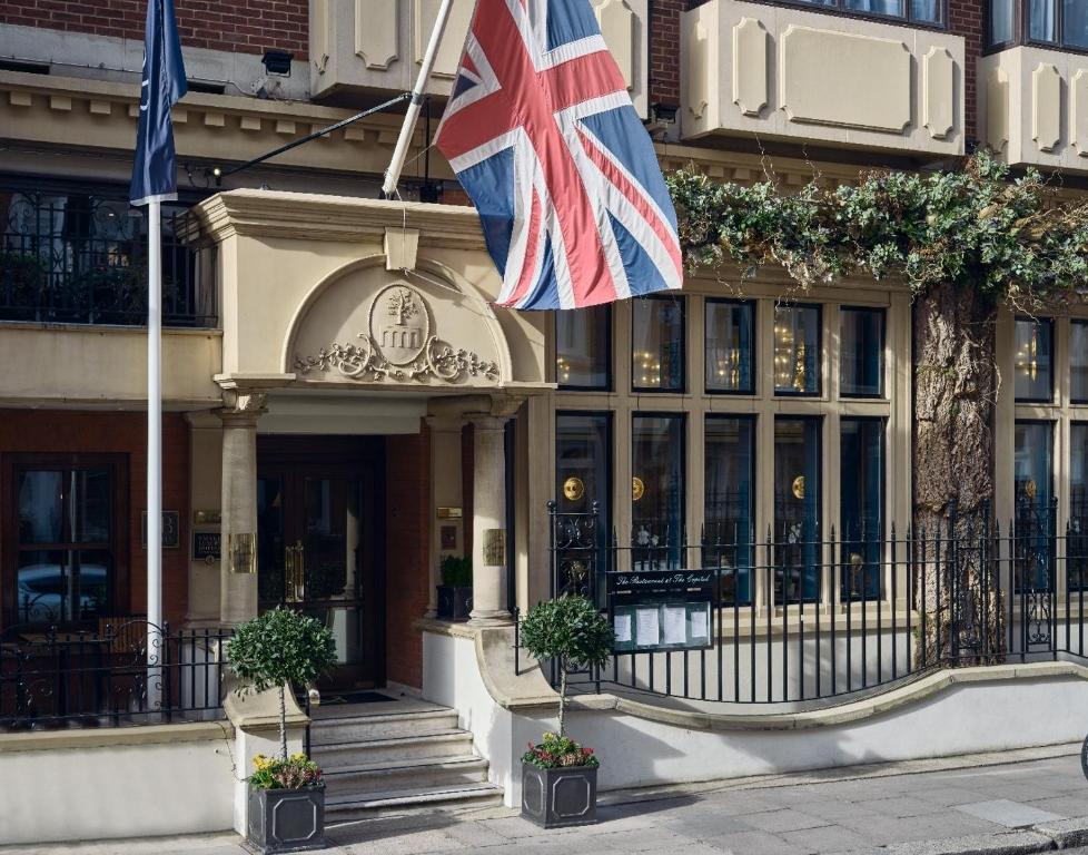 una bandera británica ondeando frente a un edificio en The Capital Hotel, Apartments & Townhouse en Londres