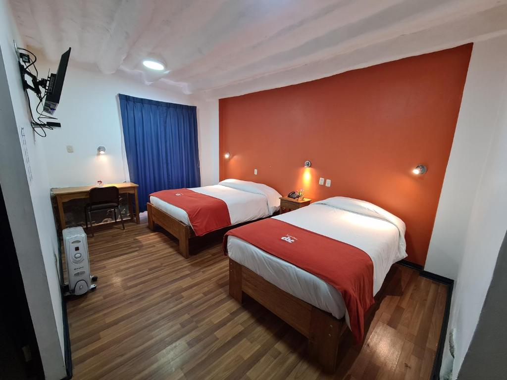 Habitación de hotel con 2 camas y escritorio en Hotel Casa Campesina, en Cusco