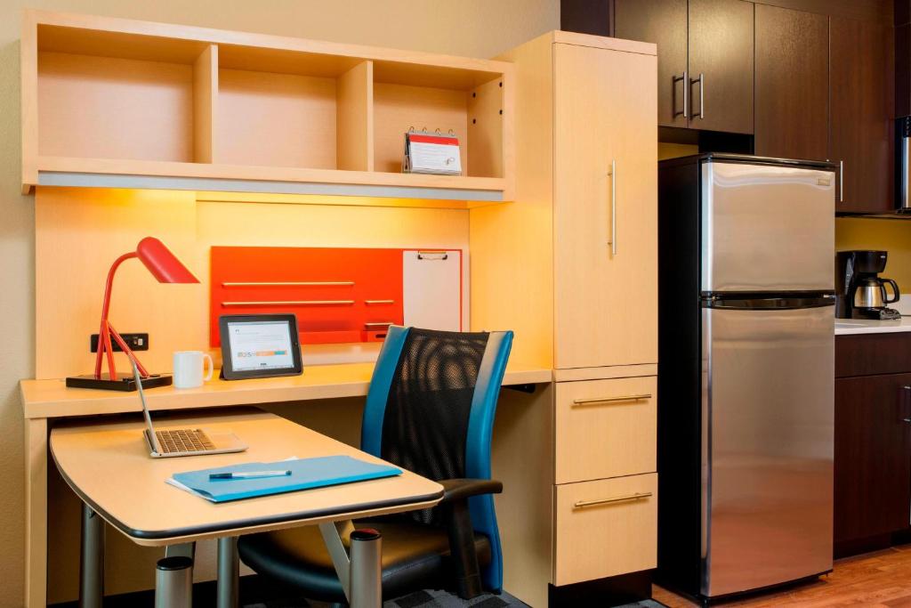 a kitchen with a desk with a laptop and a refrigerator at TownePlace Suites by Marriott Red Deer in Red Deer
