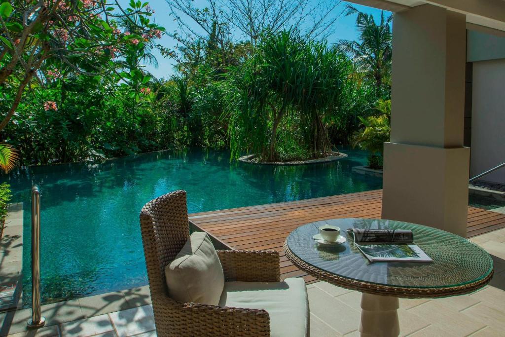 a patio with a table and chairs next to a pool at The Ritz-Carlton Bali in Nusa Dua