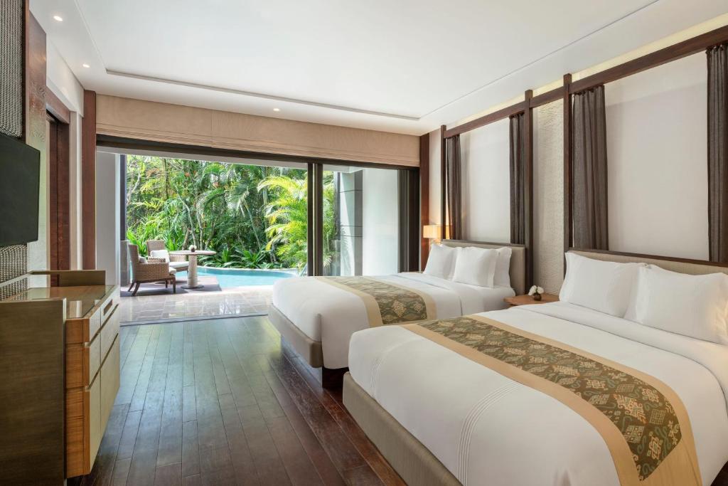 a hotel room with two beds and a television at The Ritz-Carlton Bali in Nusa Dua