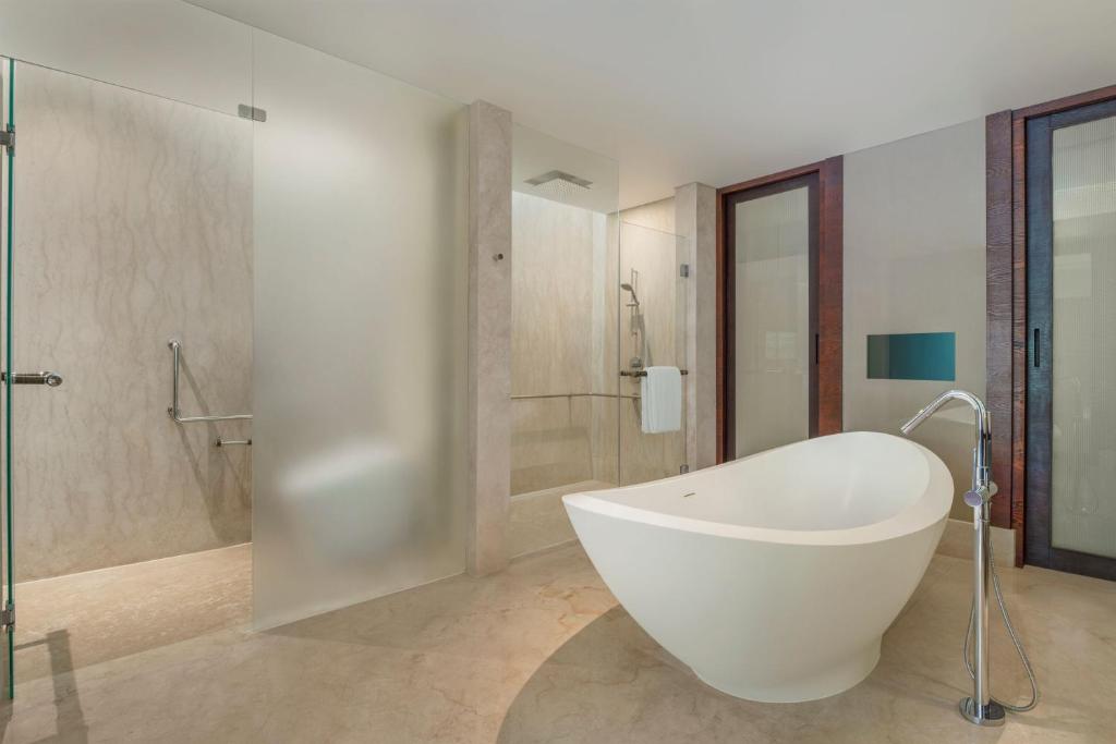 a bathroom with a large white tub and a shower at The Ritz-Carlton Bali in Nusa Dua