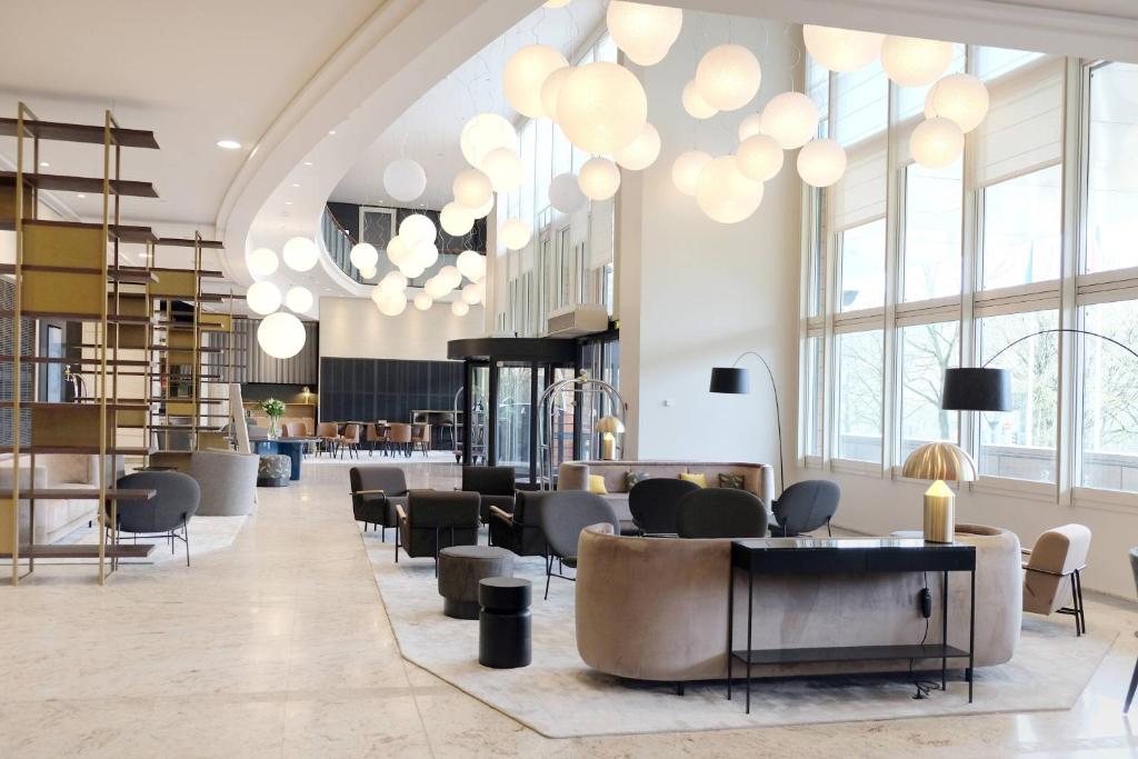 - un hall avec des chaises, des tables et de grandes fenêtres dans l'établissement Lyon Marriott Hotel Cité Internationale, à Lyon
