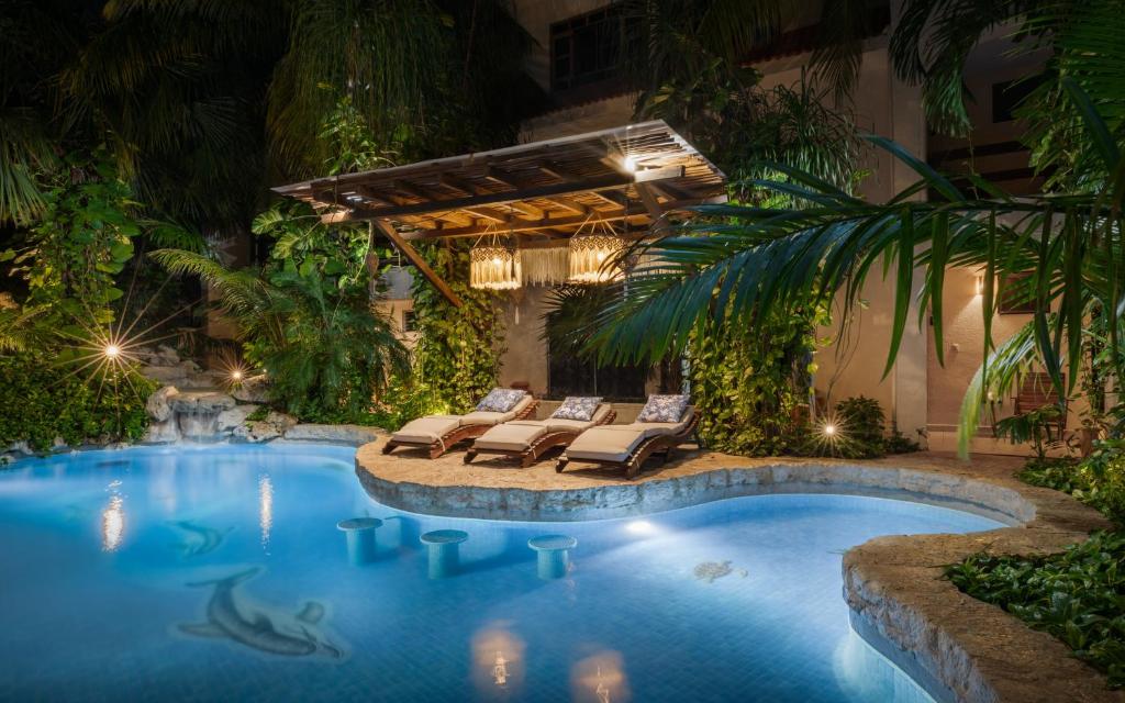 een zwembad in een tuin met ligstoelen en een resort bij Hotel Hulku in Playa del Carmen