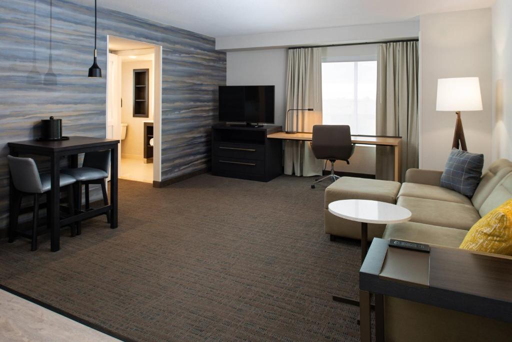 a living room with a couch and a table and a desk at Residence Inn Visalia in Visalia